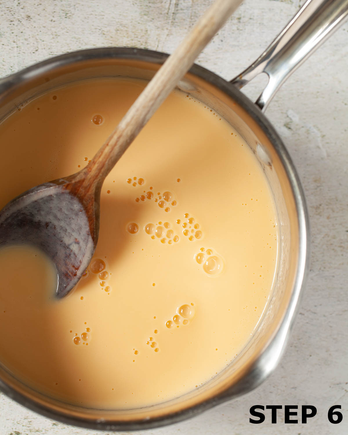 Custard in a pan with a wooden spoon in it.