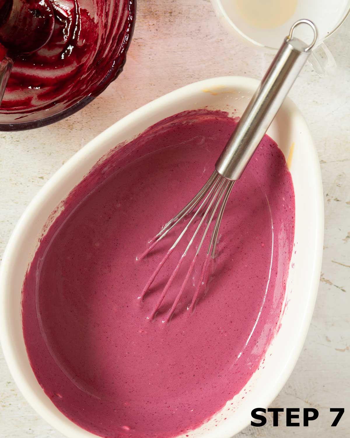 Custard base for blackcurrant ice cream in a mixing bowl with a whisk.