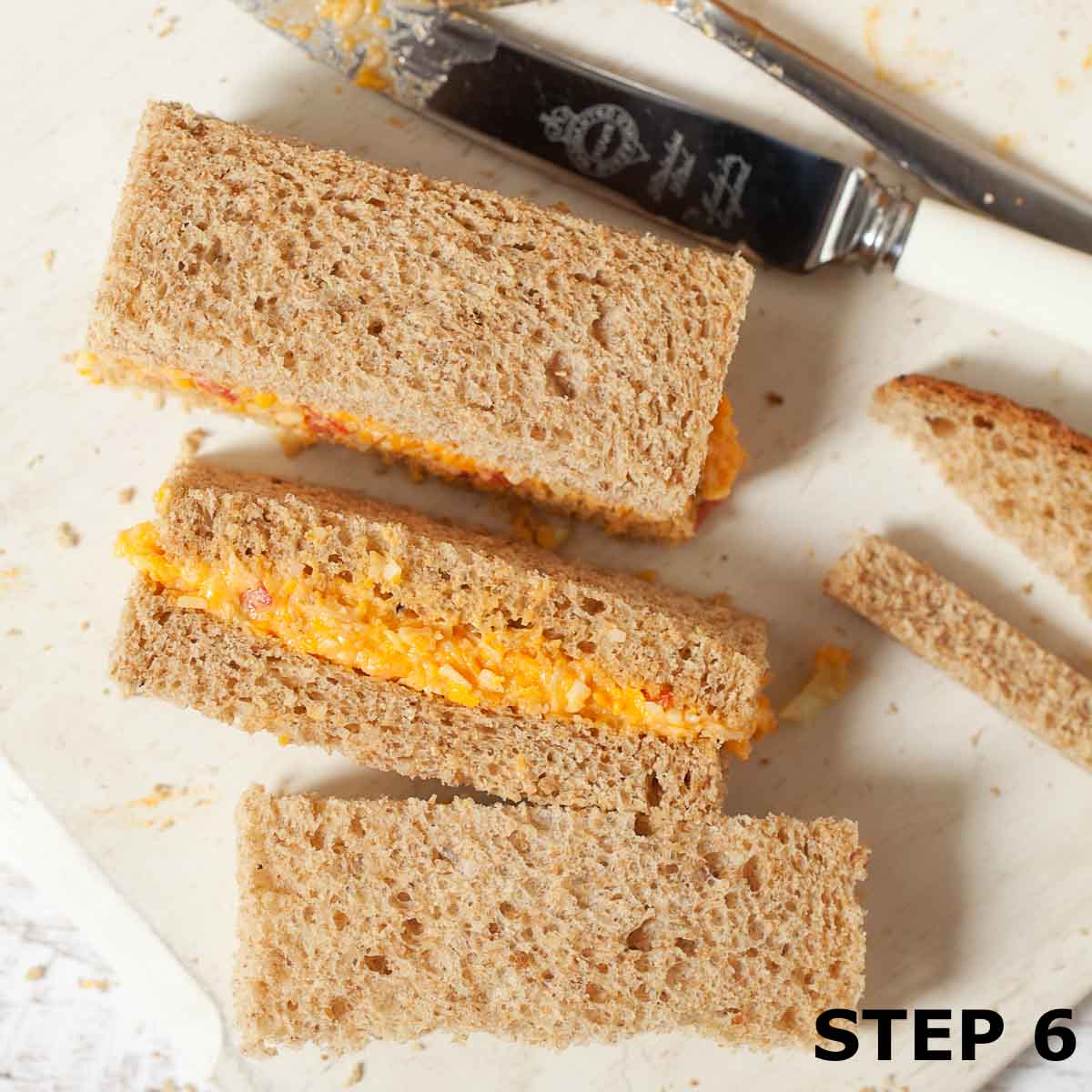 Three finger sandwiches with savoury cheese filling on brown bread.
