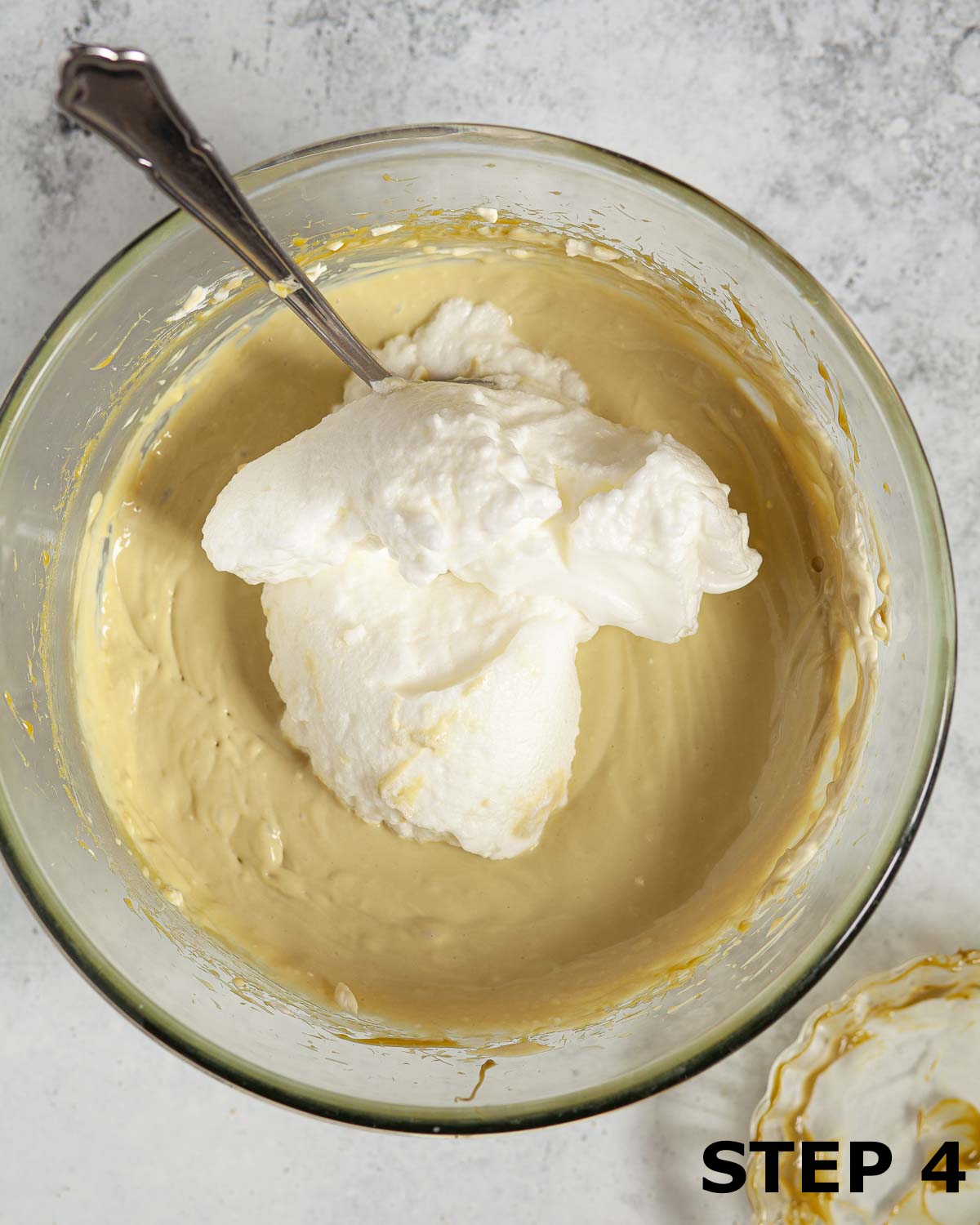 Egg whites and pistachio cream filling about to be mixed together in a bowl.
