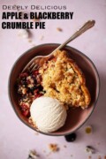 Labelled slice of blackberry crumble topped pie in a dish with vanilla ice cream.