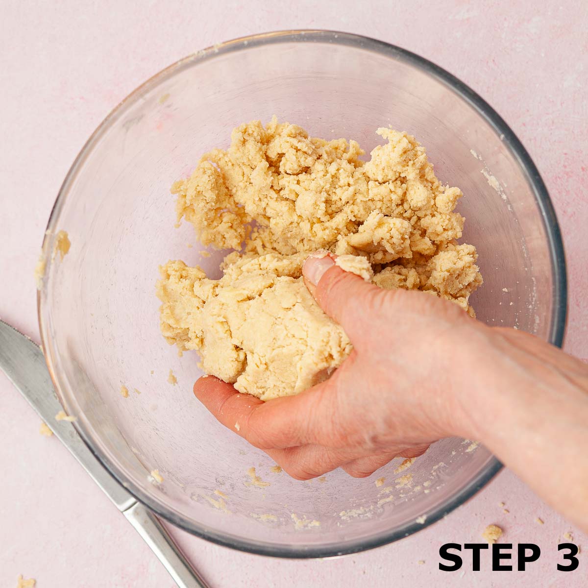 Person forming shortcrust pastry dough in a mixing bowl.