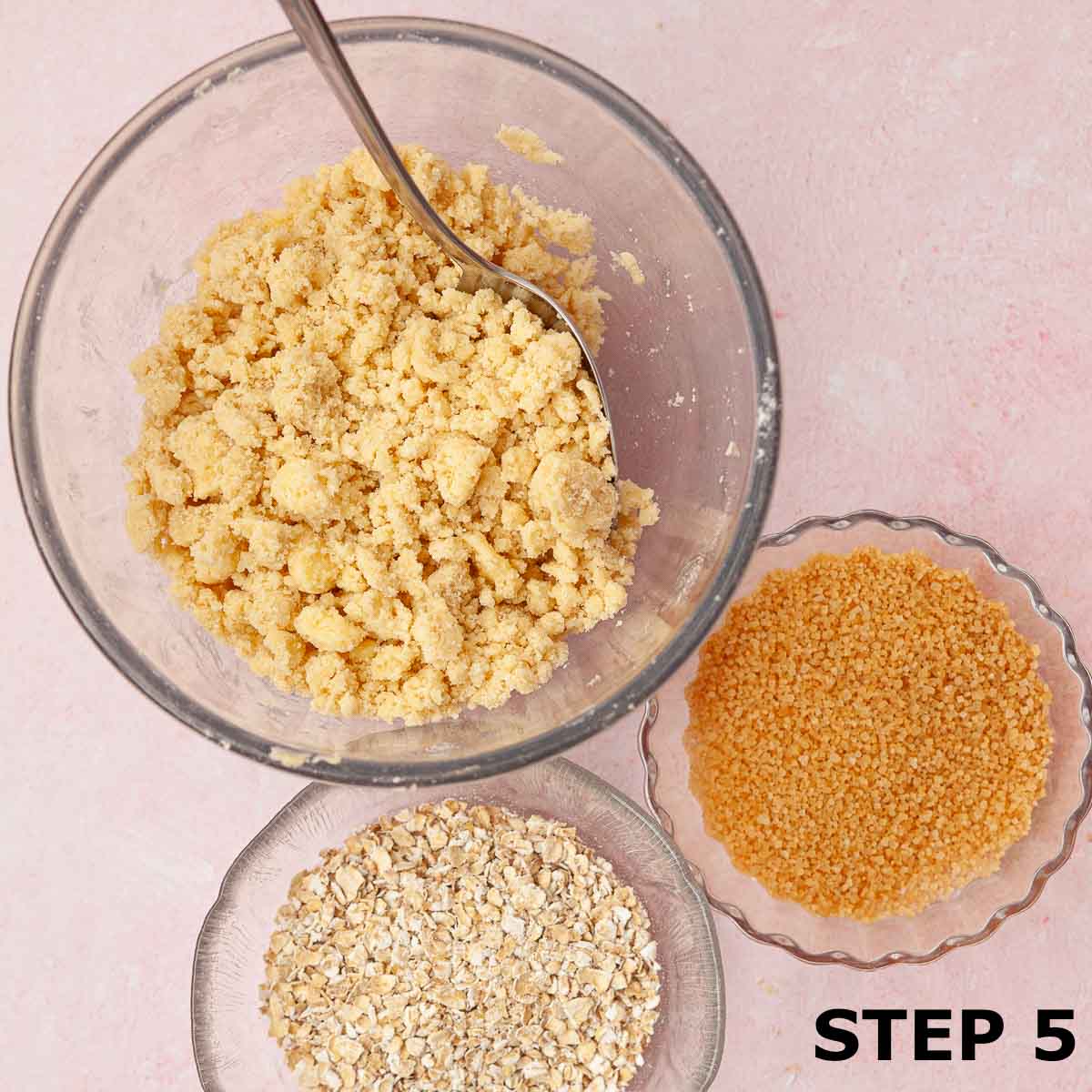Crumble topping in a bowl with oats and demerara sugar in smaller bowls.