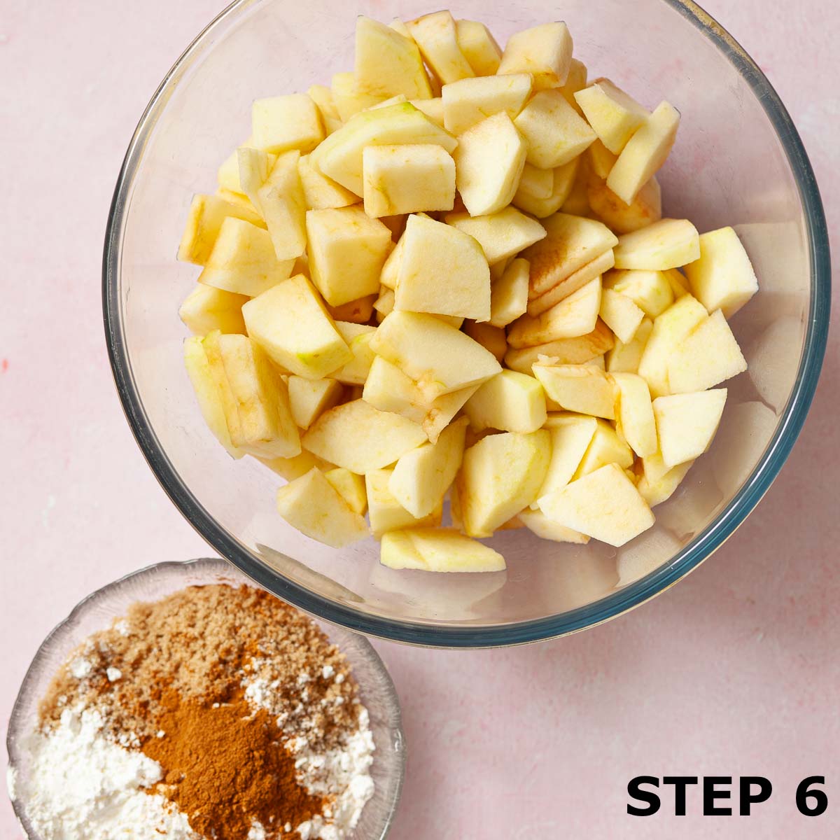 Chopped apple in a bowl with cornflour, brown sugar and cinnamon in a smaller bowl.