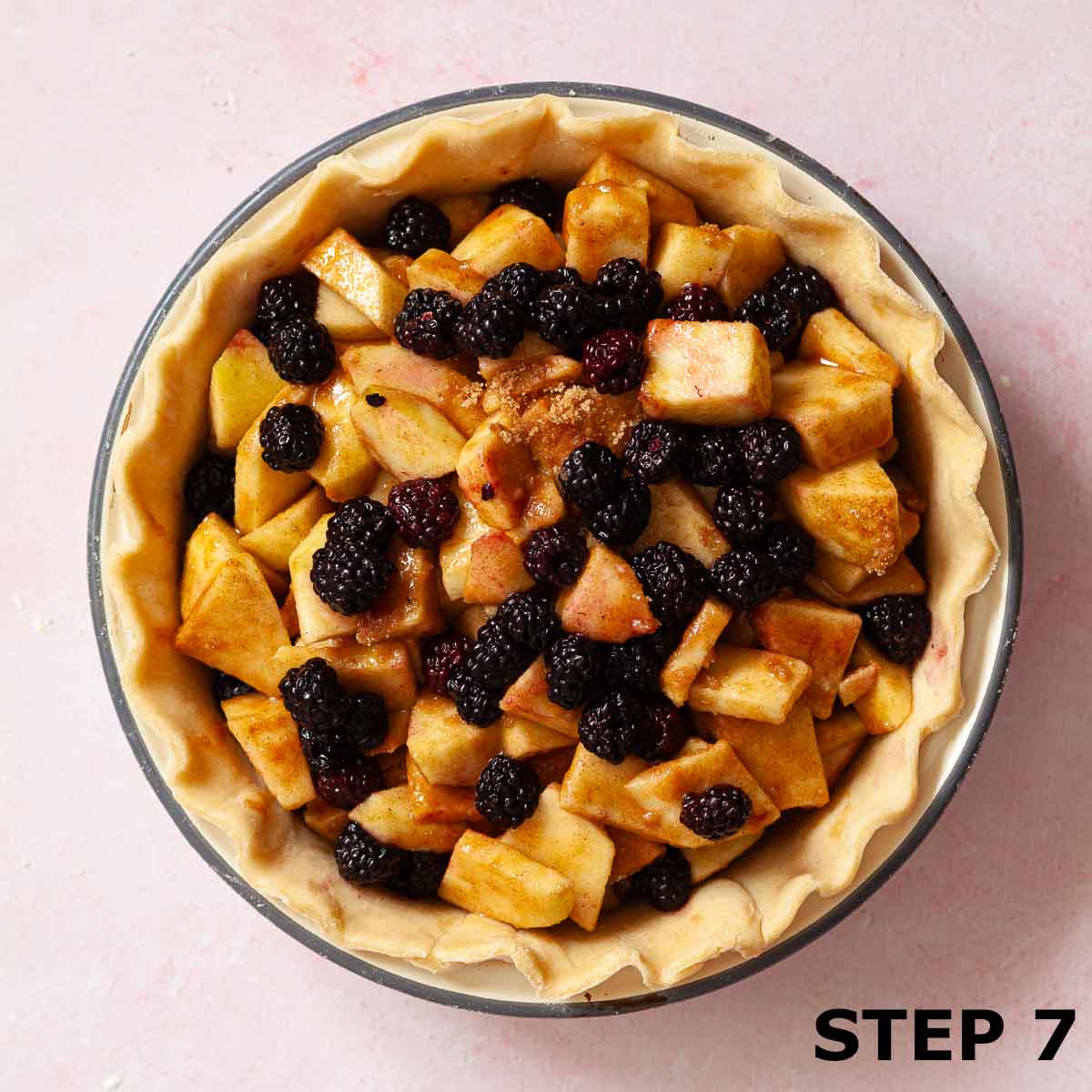 Apple and blackberries in a pie dish lined with shortcrust pastry.