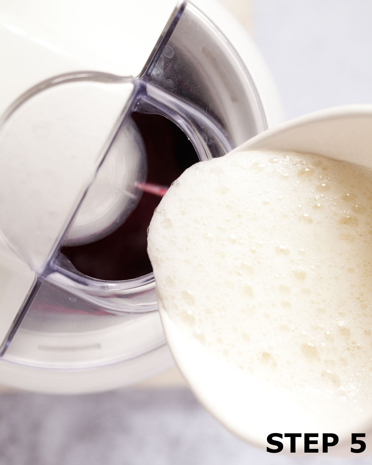 Whisked egg white being poured into an ice cream churner making sorbet.