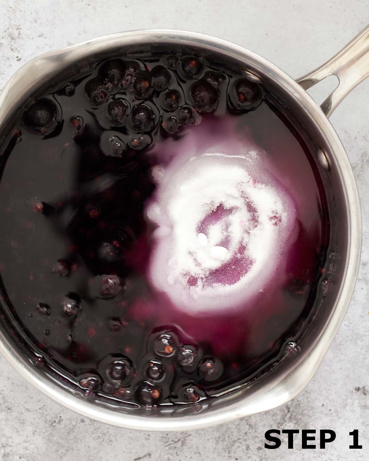 Blackcurrants, water and sugar in a saucepan.