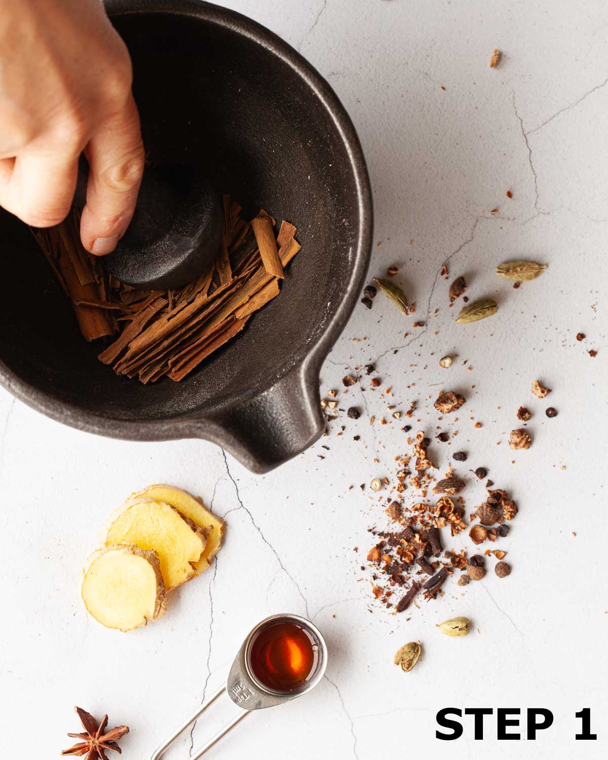 A person crushing cinnamon using a pestle and mortar.
