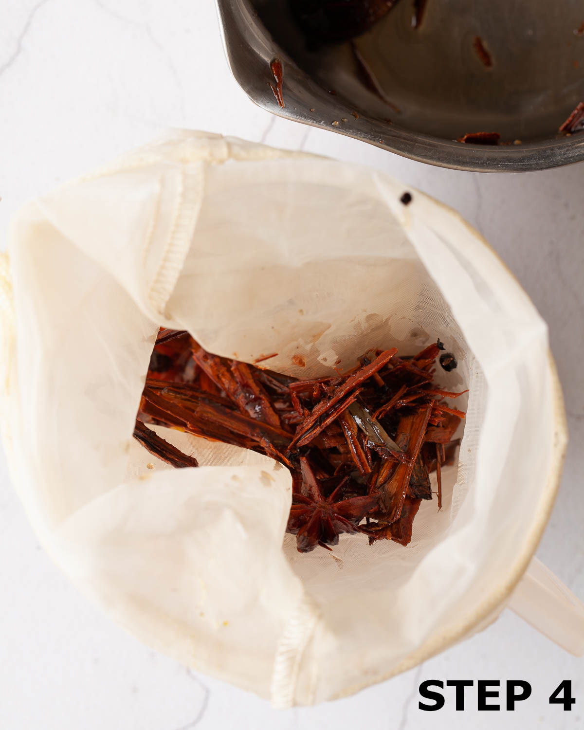 Spices being strain through a nut bag when making chai syrup.