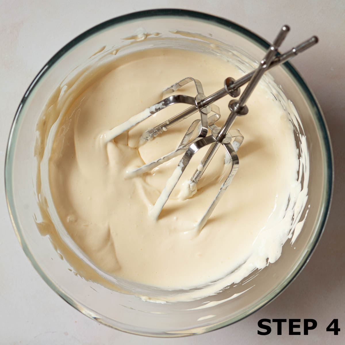 Bowl of creamy mascarpone filling for tiramisu with beaters in the bowl.