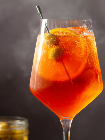 Spritz Veneziano with orange slice and green olive garnish.