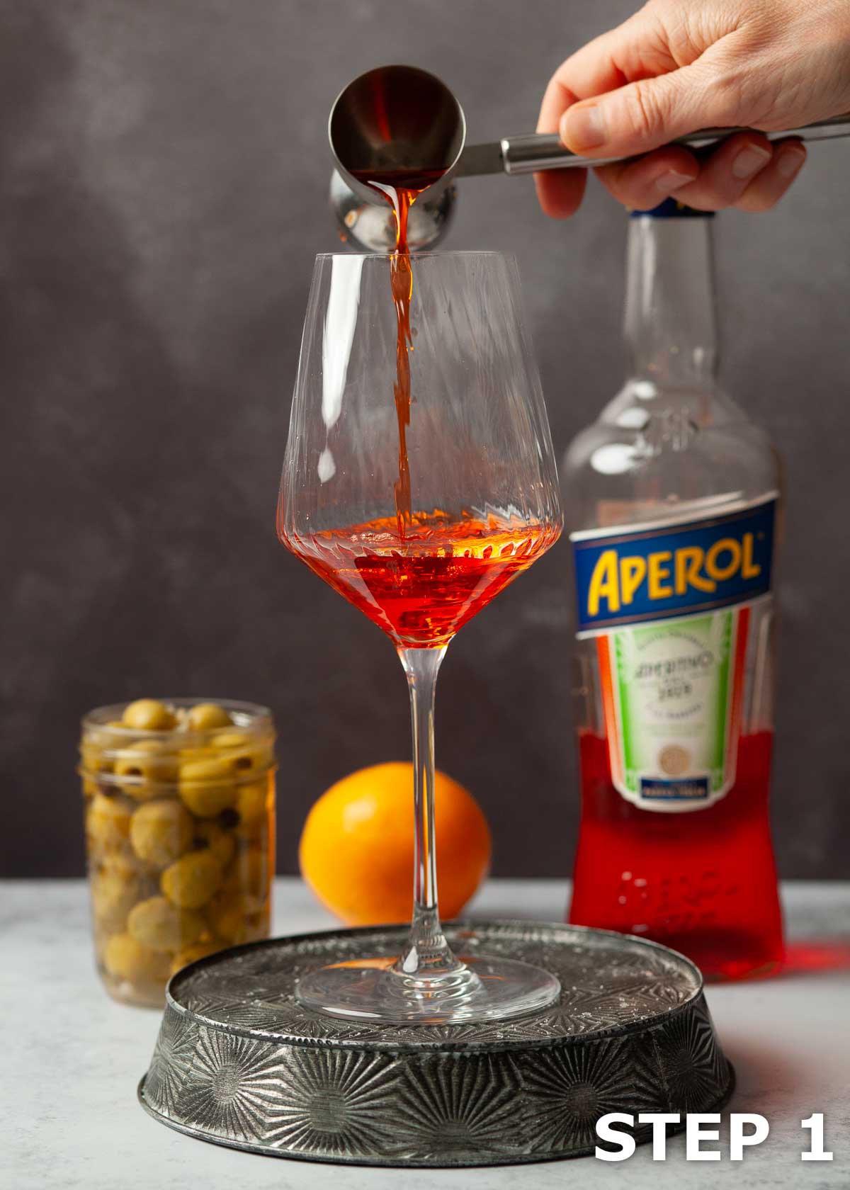 A person pouring Aperol into a glass.