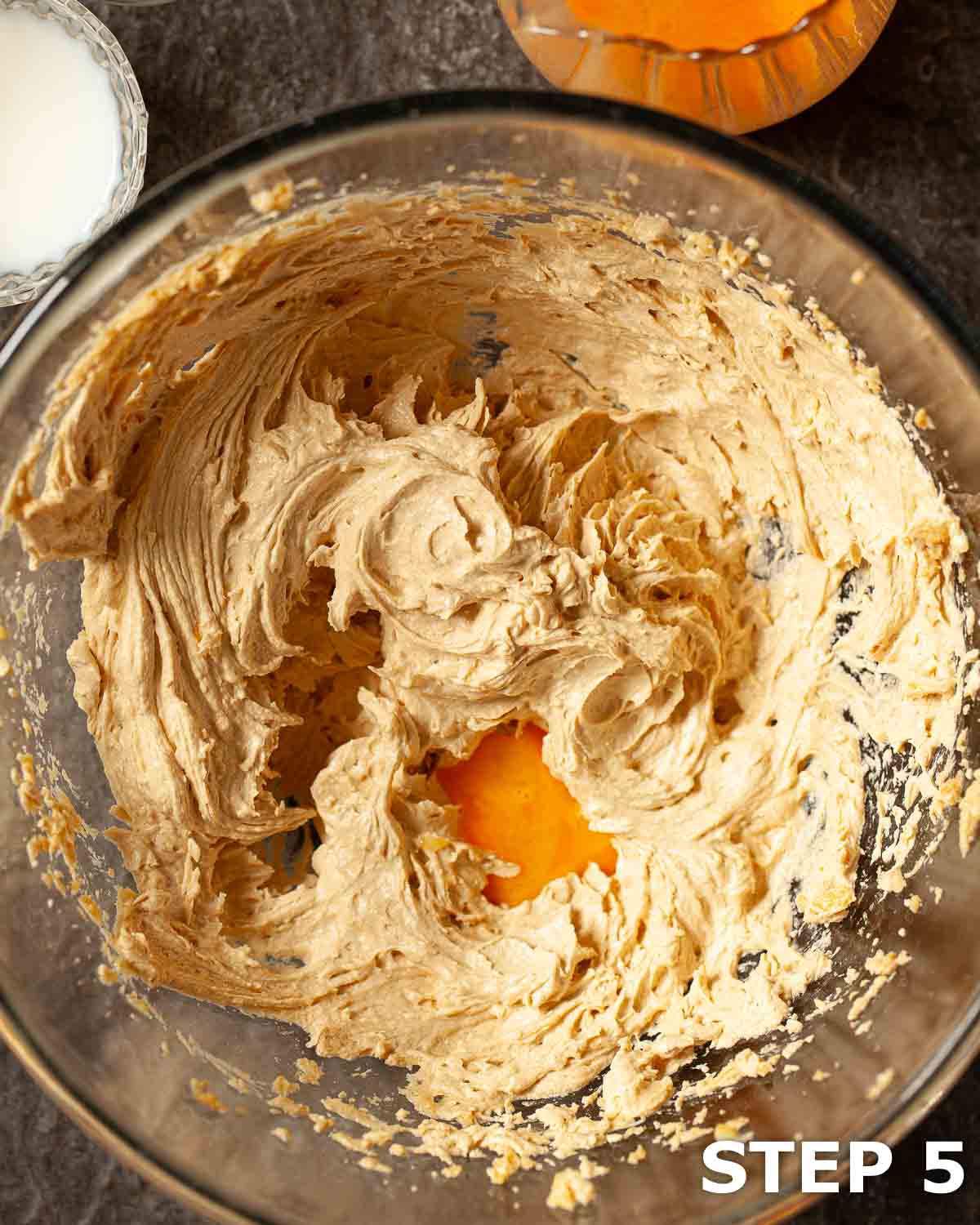 Eggs being gradually added to creamed butter and sugar to make cake batter.