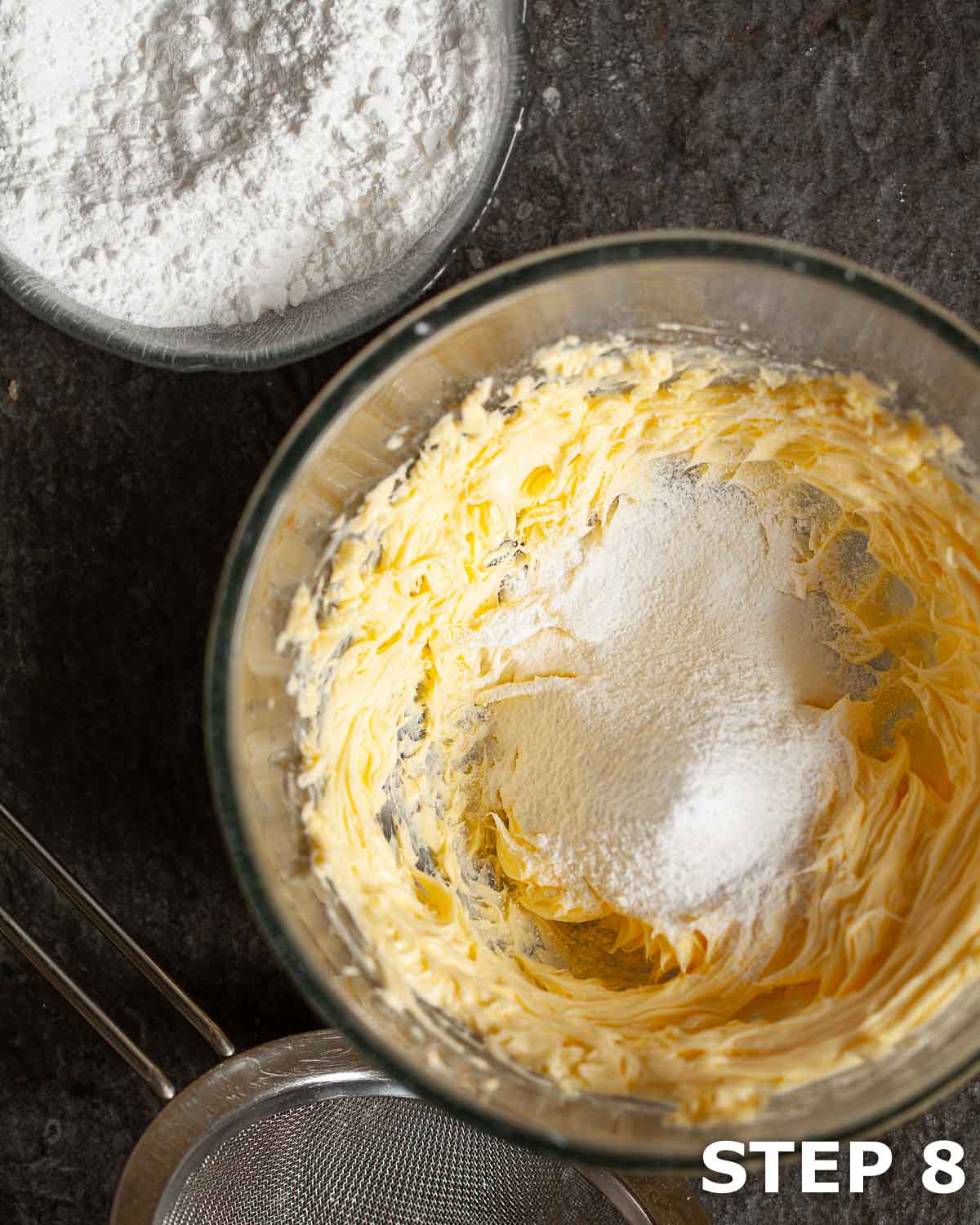 Adding sieved icing sugar to creamed butter in a mixing bowl to make buttercream.
