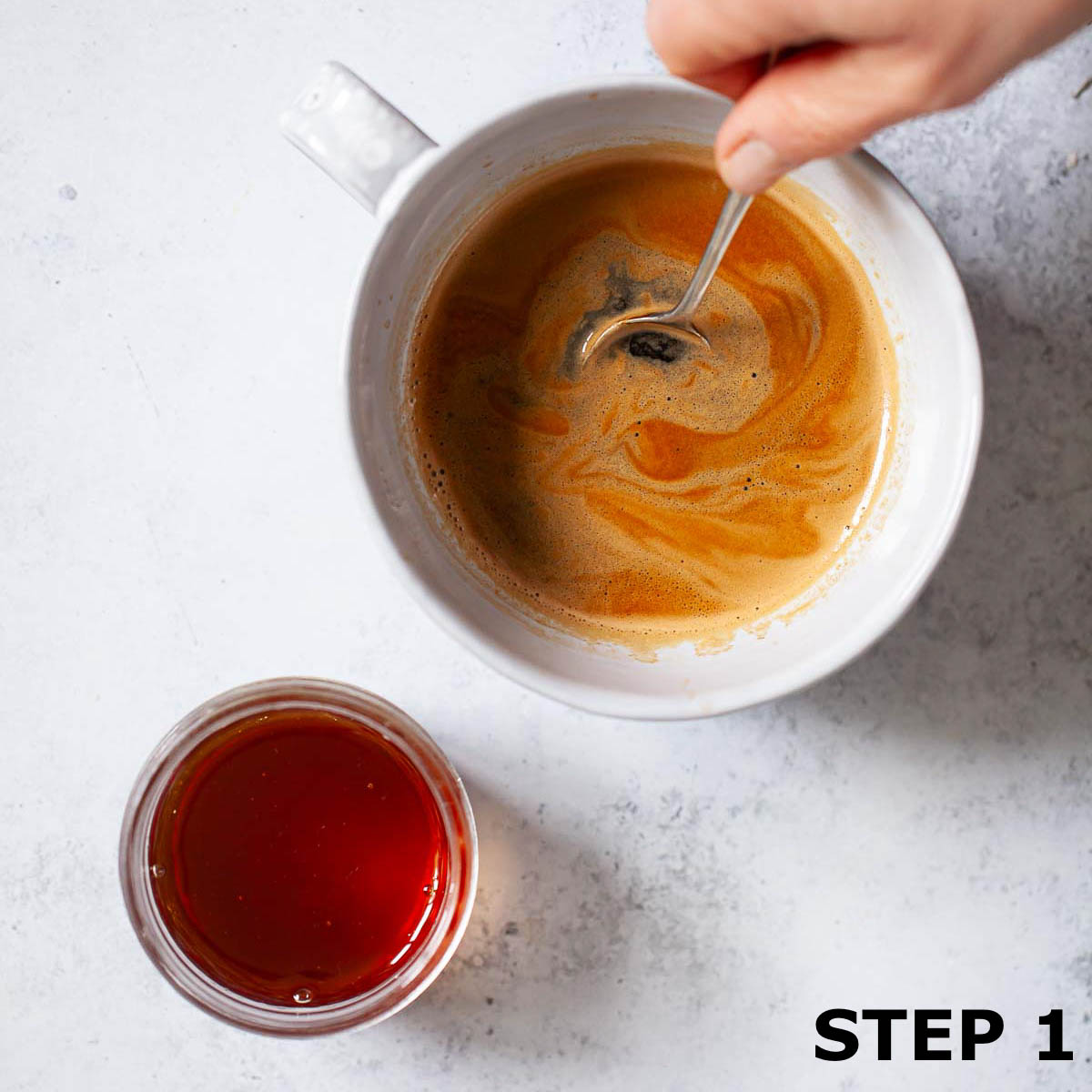 Person stirring honey into a cup of espresso coffee.