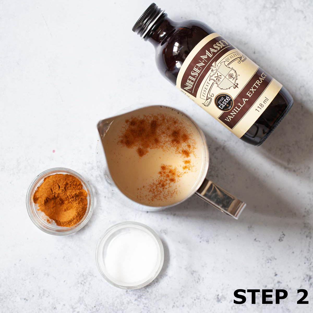 Oat milk in a jug with cinnamon,salt and vanilla extract alongside.