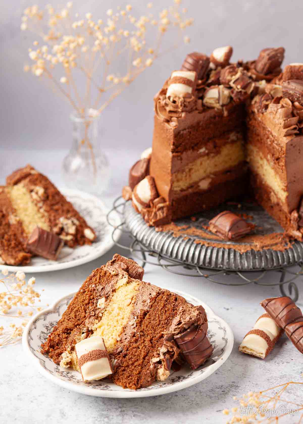 A slice of Kinder Bueno birthday cake with the rest of the cake in the background.