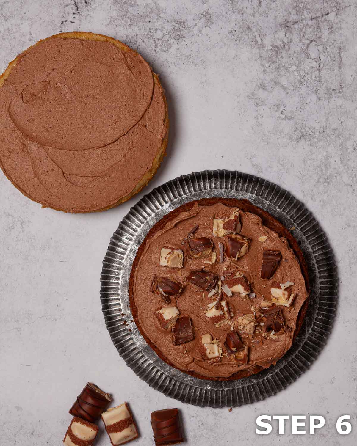 Nutella buttercream spread over sponge cake with Bueno pieces scattered on top.