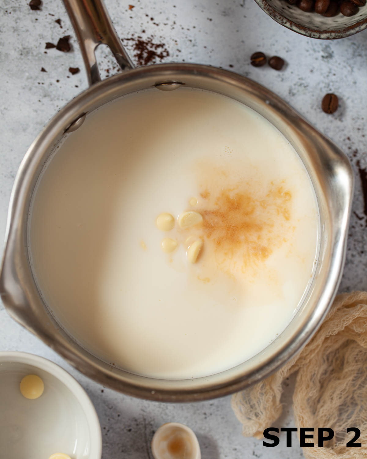 White chocolate chips and vanilla extract in a pan of hot milk.