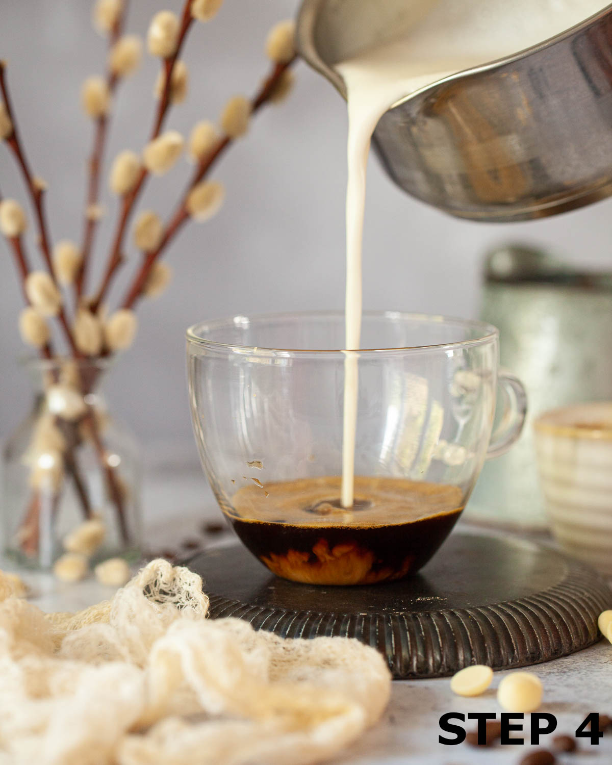 Hot white chocolate being poured over espresso coffee to make white mocha.