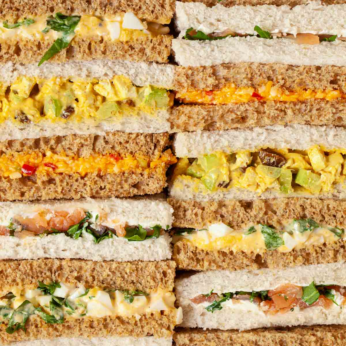 Rows of finger sandwiches with different fillings for an afternoon tea selection.