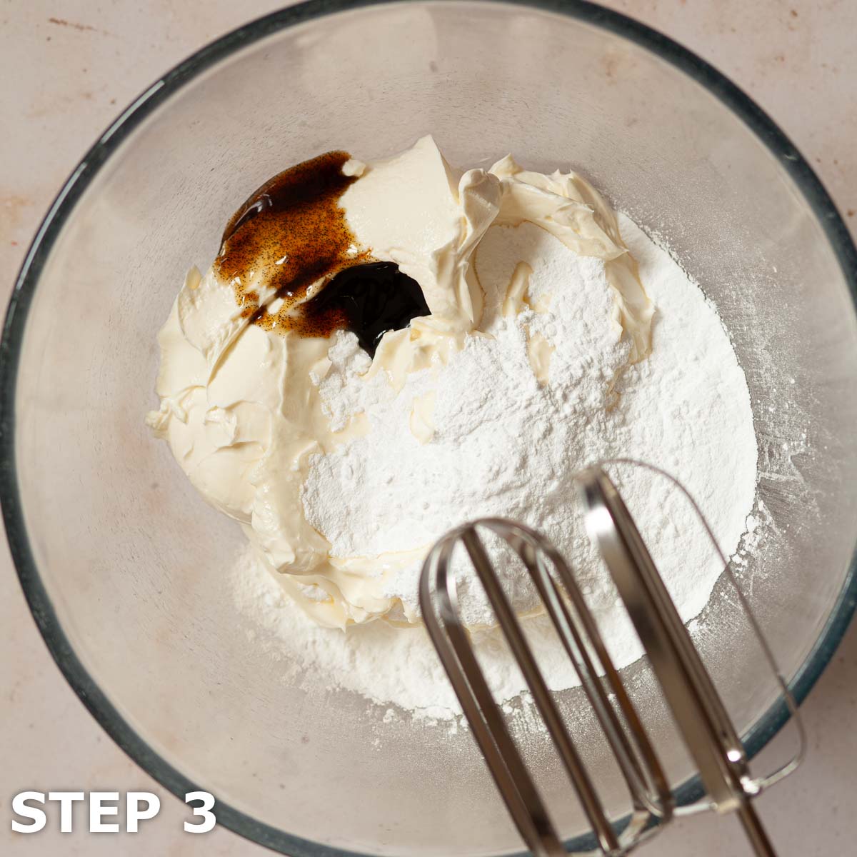 Ingredients for no bake cheesecake batter in a mixing bowl with electric beater alongside.