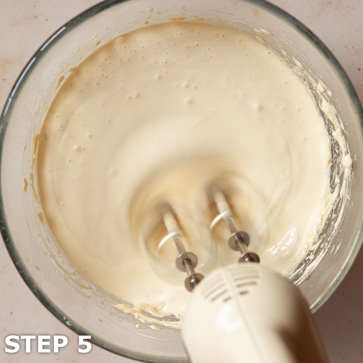 Irish cream cheesecake batter being whipped with electric beaters.