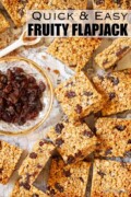 Squares of fruit flapjack with a plate of raisins alongside with text overlay.