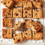 Squares of fruit flapjack on a sheet of patterned parchment.