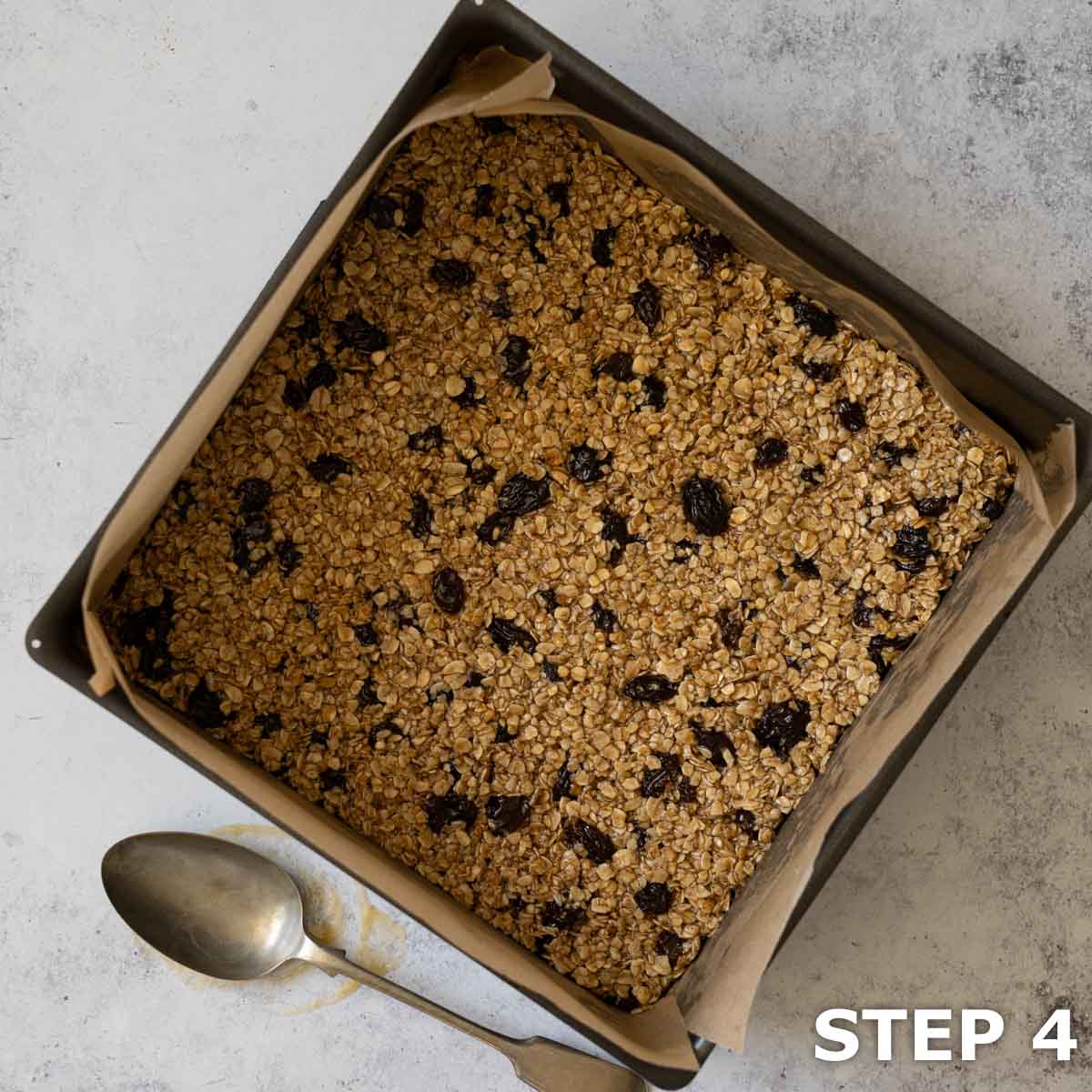 Fruit flapjack mixture pressed into a lined baking tin ready to be cooked.