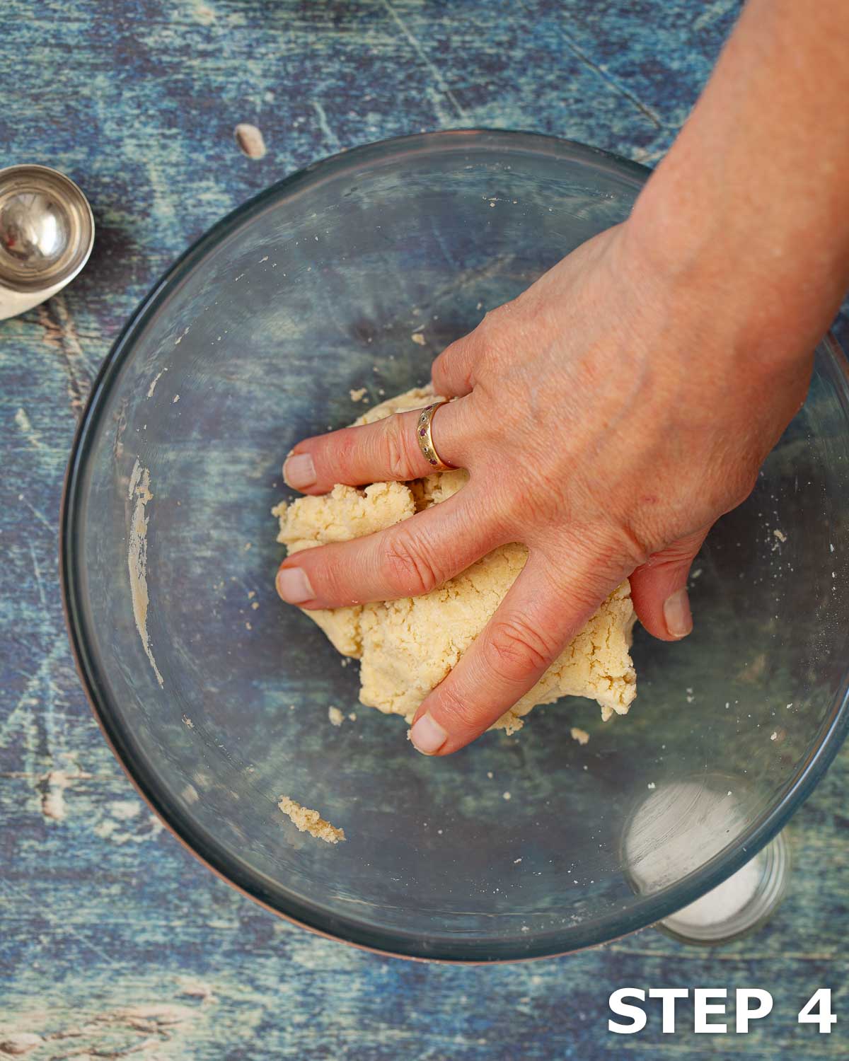 Person forming pastry dough into a ball in a mixing bowl.