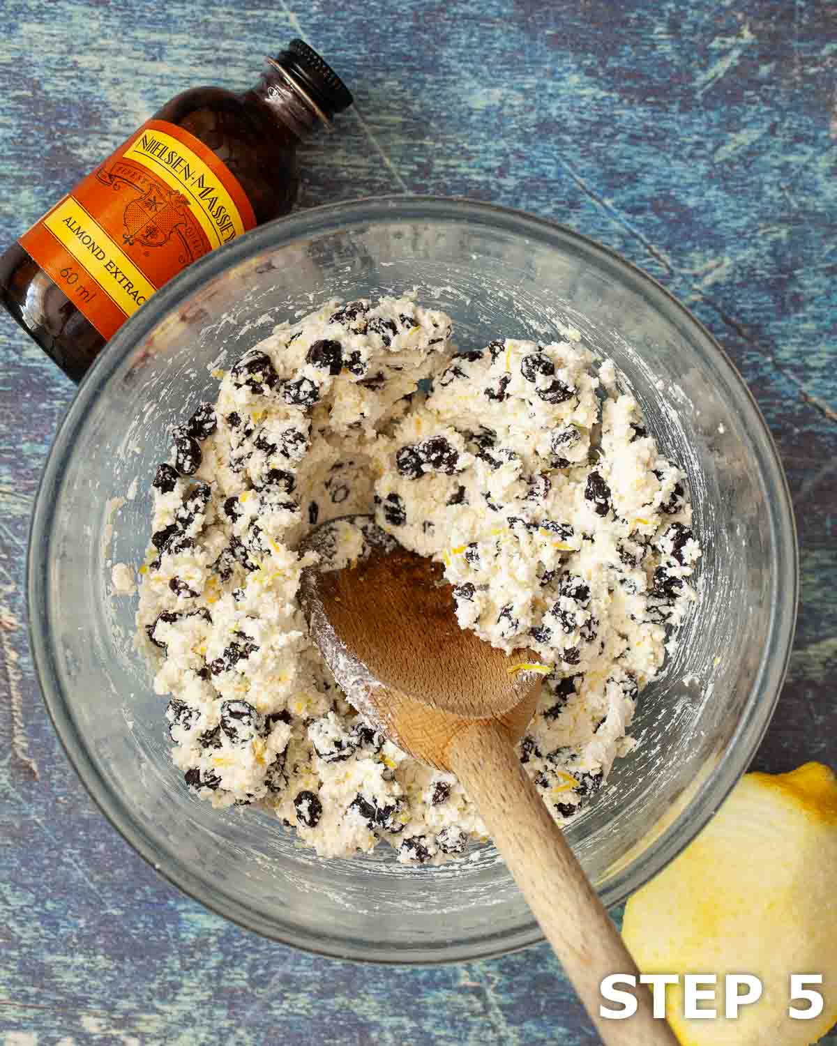 Curd cheese mixed with currants, almond extract and lemon zest in a mixing bowl.