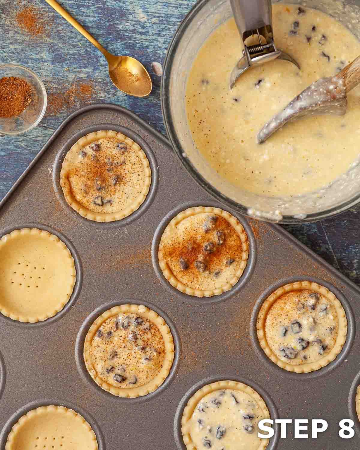 Curd cheesecake batter being transferred into pastry shells and sprinkled with nutmeg.