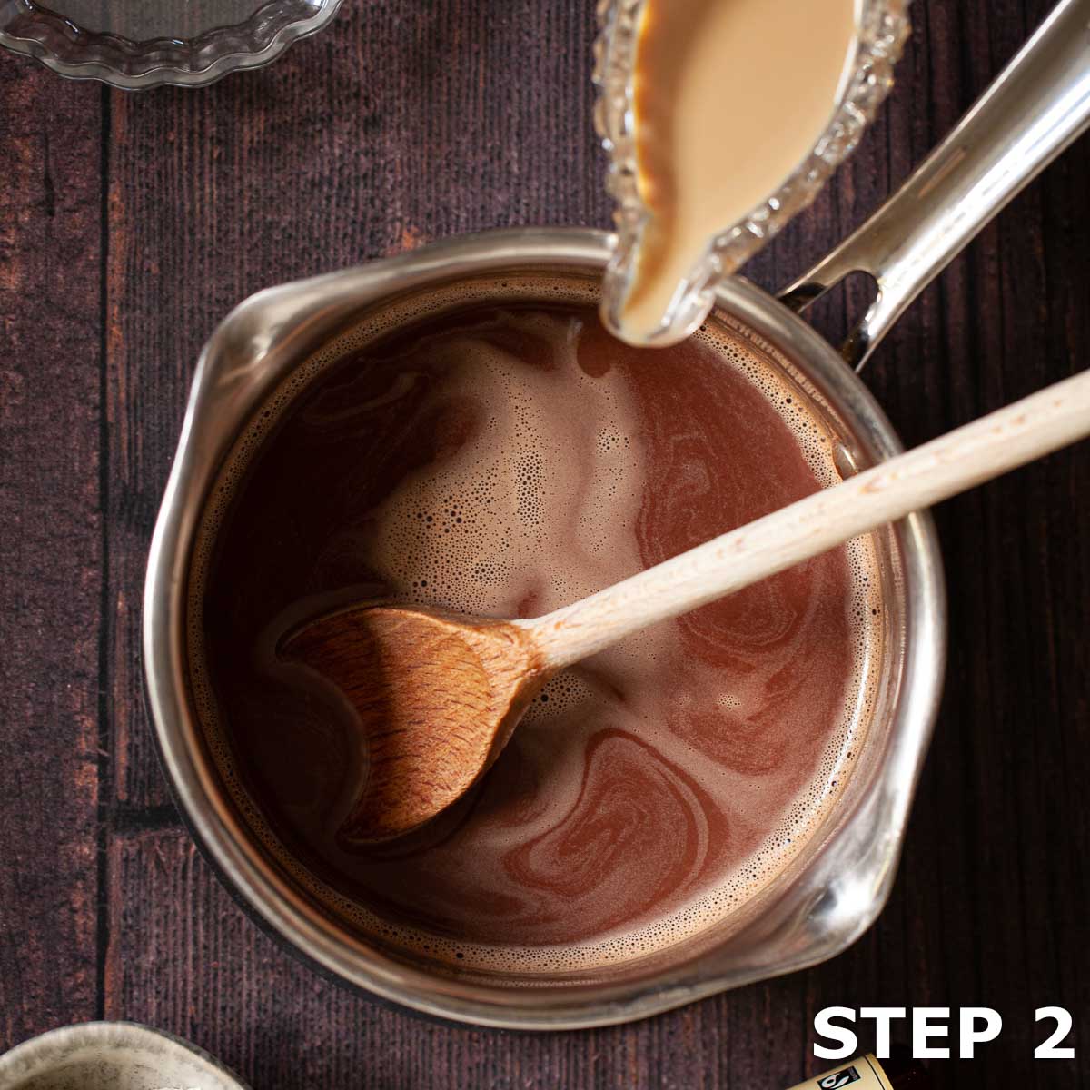 Irish cream being poured into hot chocolate in a saucepan.