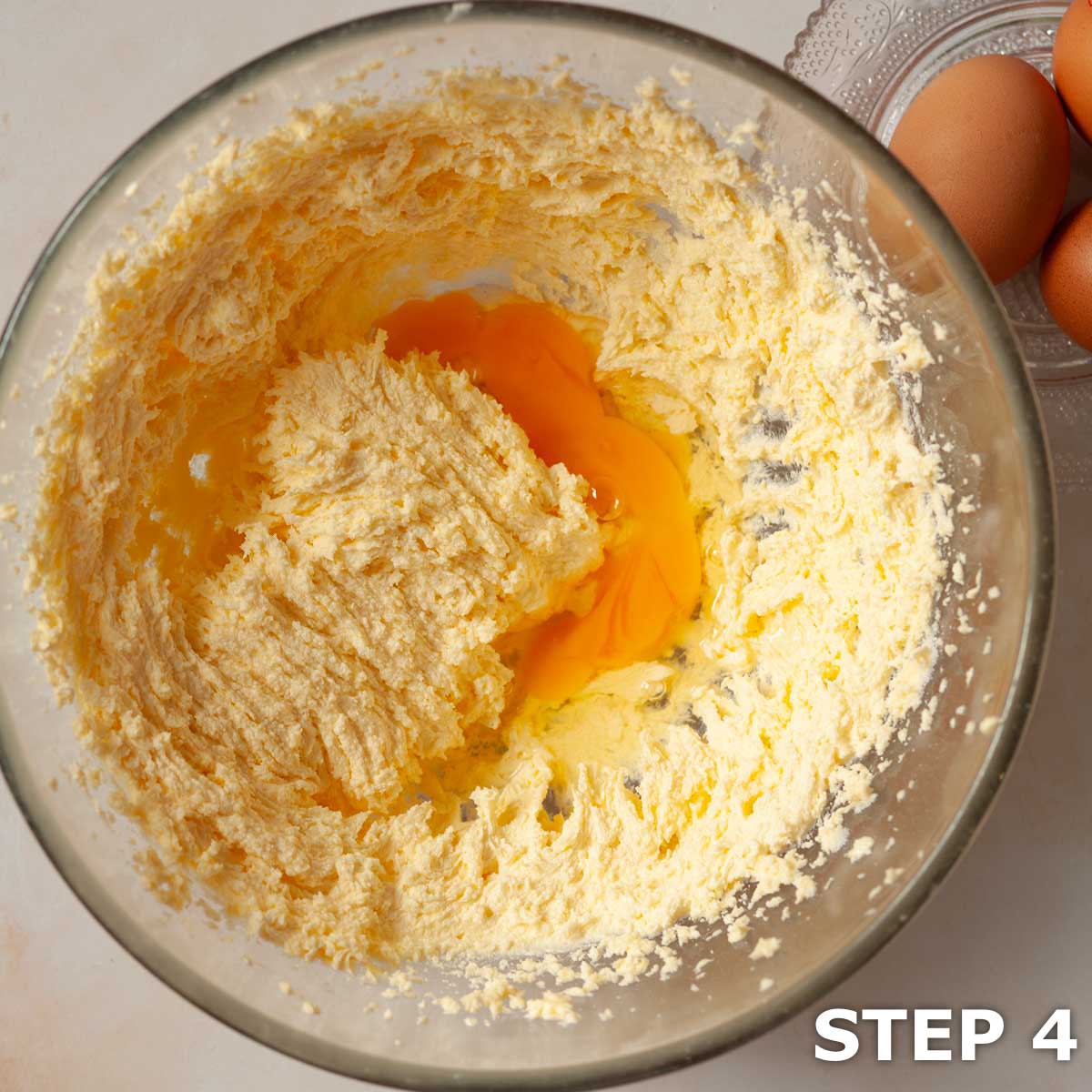 Egg in a mixing bowl containing creamed butter and sugar.