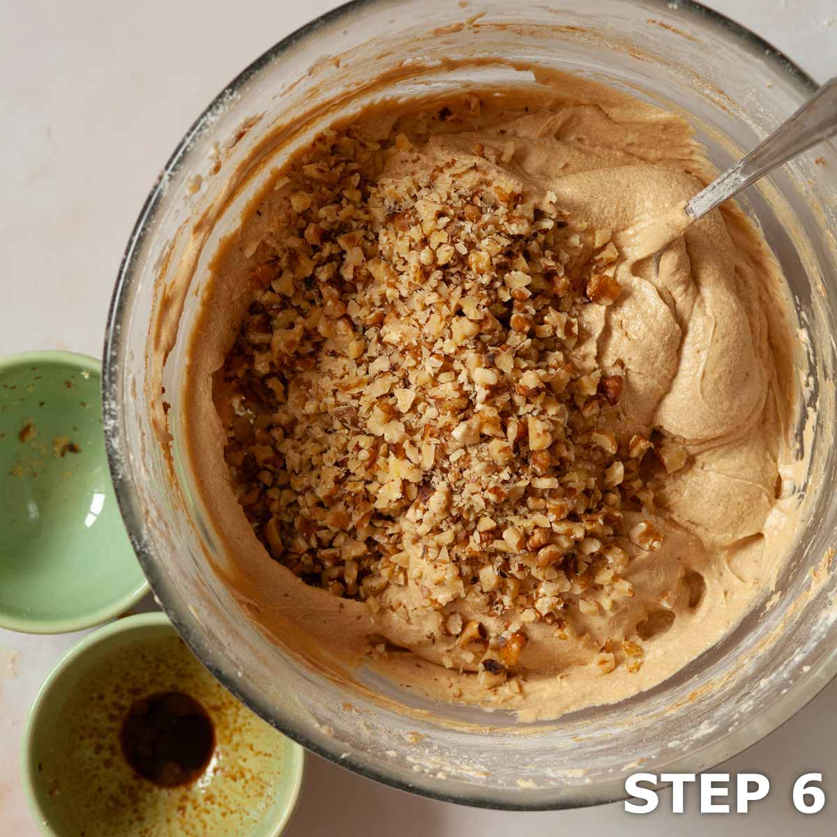 Chopped walnuts in a bowl of coffee cake batter.