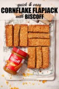 Labelled cornflake flapjack slices with a jar of Biscoff spread next to them.