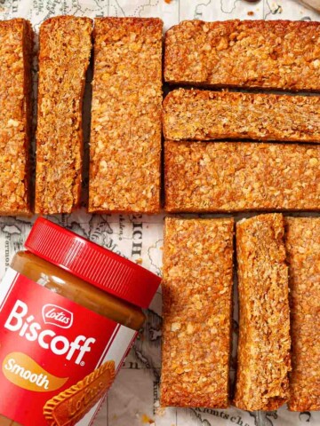Slice of cornflake flapjack on a board with a jar of Biscoff spread alongside them.