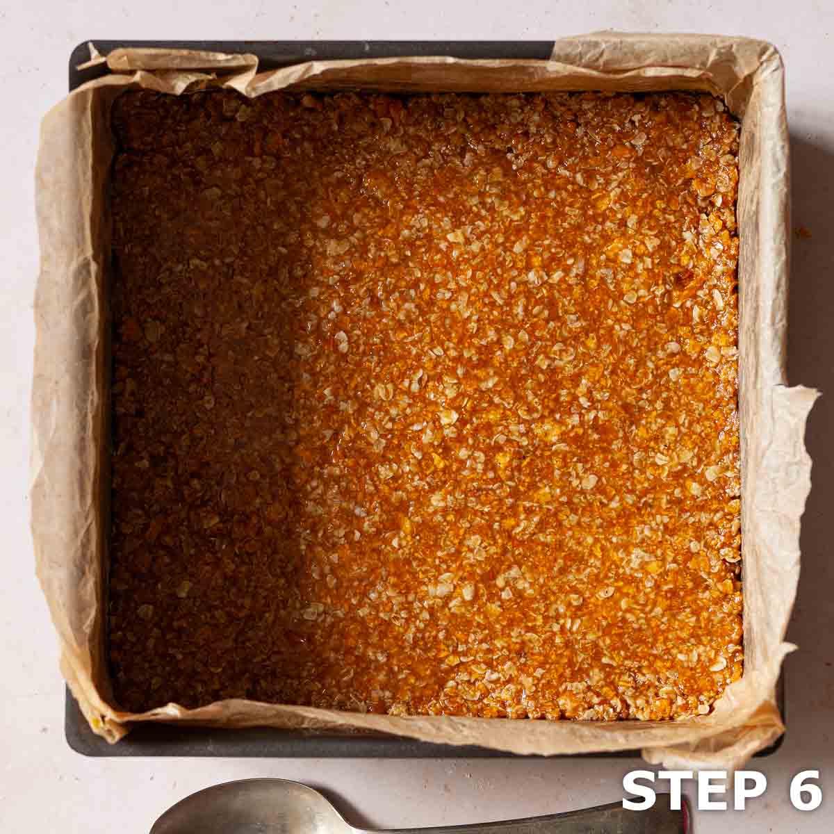 Cornflake flapjack mixture in a baking tin ready to be cooked.