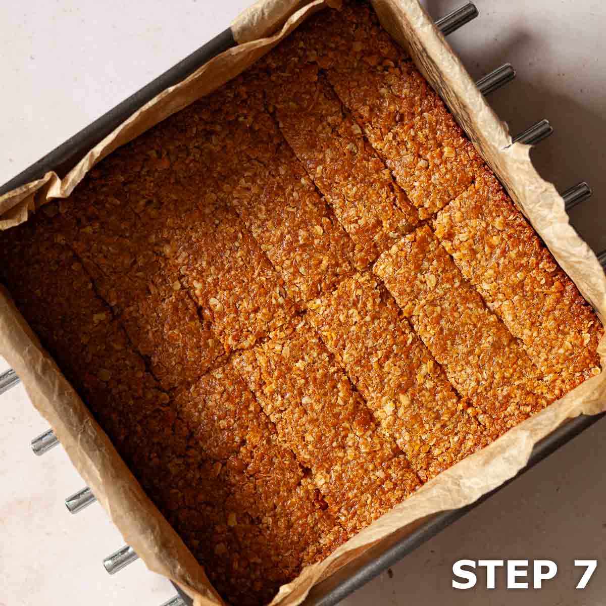 Baked cornflake flapjack in a baking tin with score marks on the top.