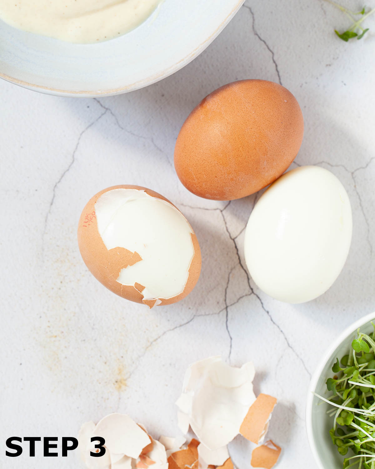 Hard boiled eggs mid-way through having the shells removed.