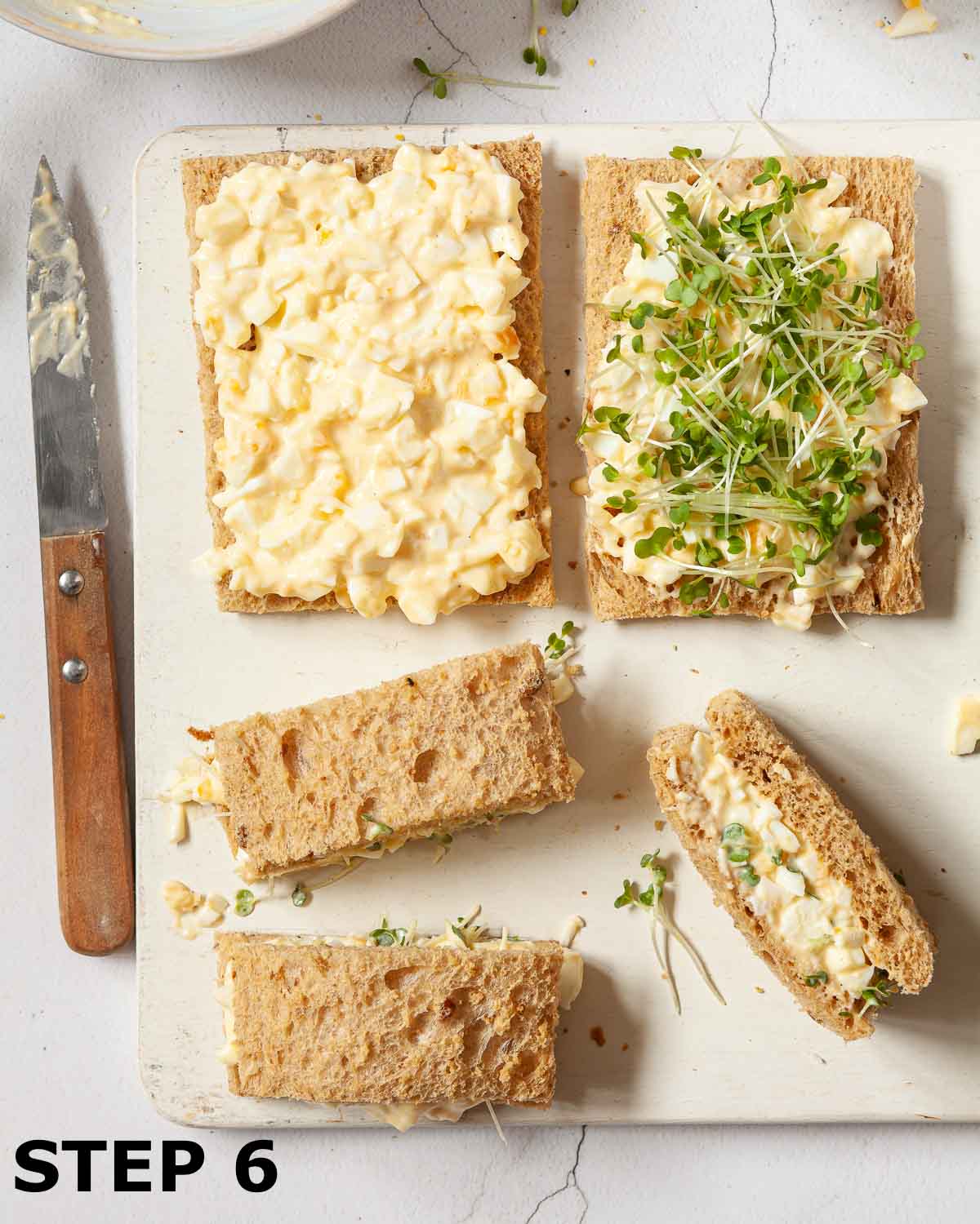 Egg mayo and cress sandwiches being assembled on a chopping board.