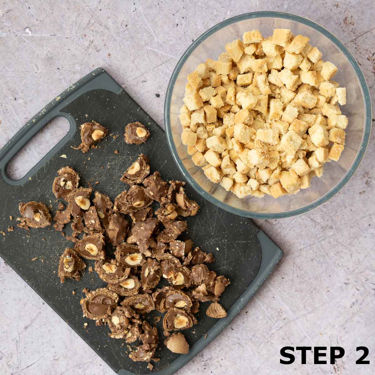 Chopped shortbread biscuits in a bowl and chopped Ferrero Rocher chocolates on a chopping board.