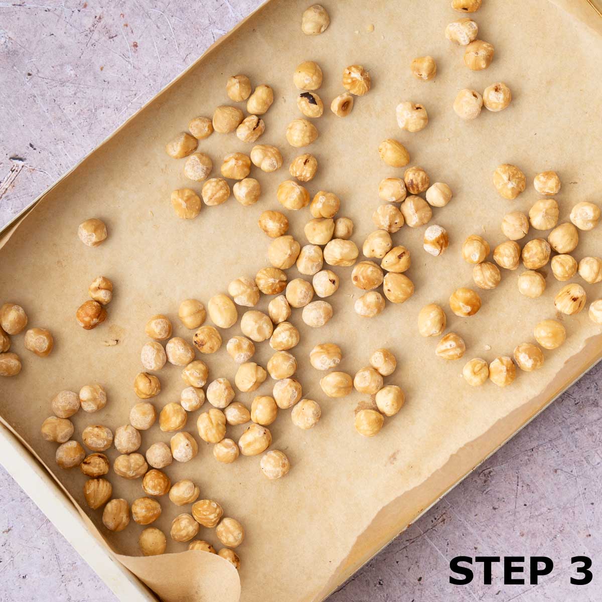 Blanched hazelnuts in a baking tin lined with baking parchment.