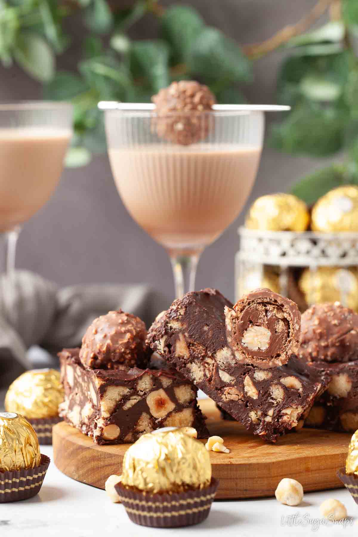 Ferrero Rocher tiffin slices with wrapped chocolates and a glass of chocolate liqueur.