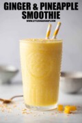 Labelled ginger and pineapple smoothie in a glass with 2 straws.