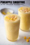 Two glasses of ginger, pineapple and orange smoothie topped with coconut with text overlay.