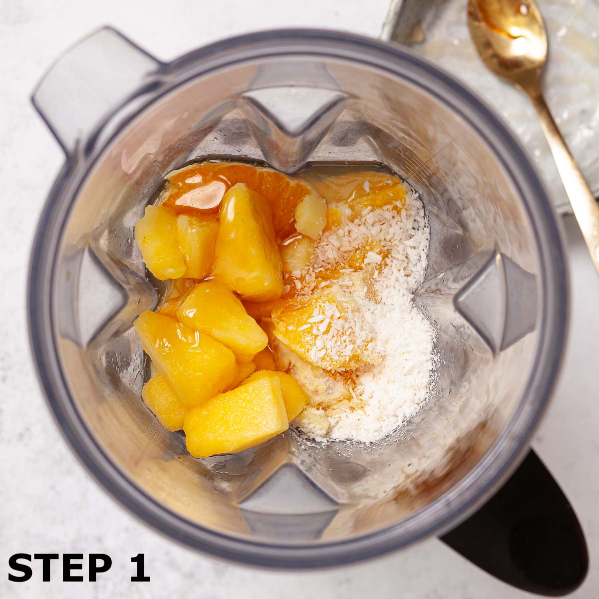 Ingredients for smoothie in a blender jug including pineapple, coconut, honey, orange and ginger.