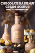 A bottle of labelled chocolate hazelnut liqueur surrounded by smaller bottles and Ferrero Rocher chocolates.