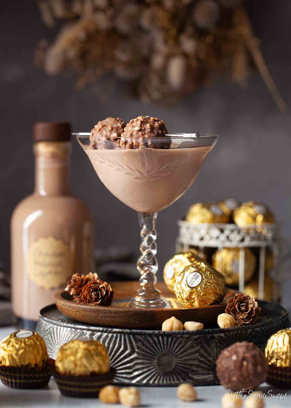 Chocolate liqueur drink in a vintage glass garnished with Ferrero Rocher chocolates on a cocktail pick.